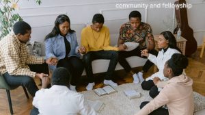 A diverse group of people (family, friends, or a small church group) in a warm, collaborative setting, with one person gently encouraging or supporting another, illustrating community and fellowship.