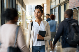 A young believer standing calmly while colleagues or fellow students move around them, showing conviction without confrontation